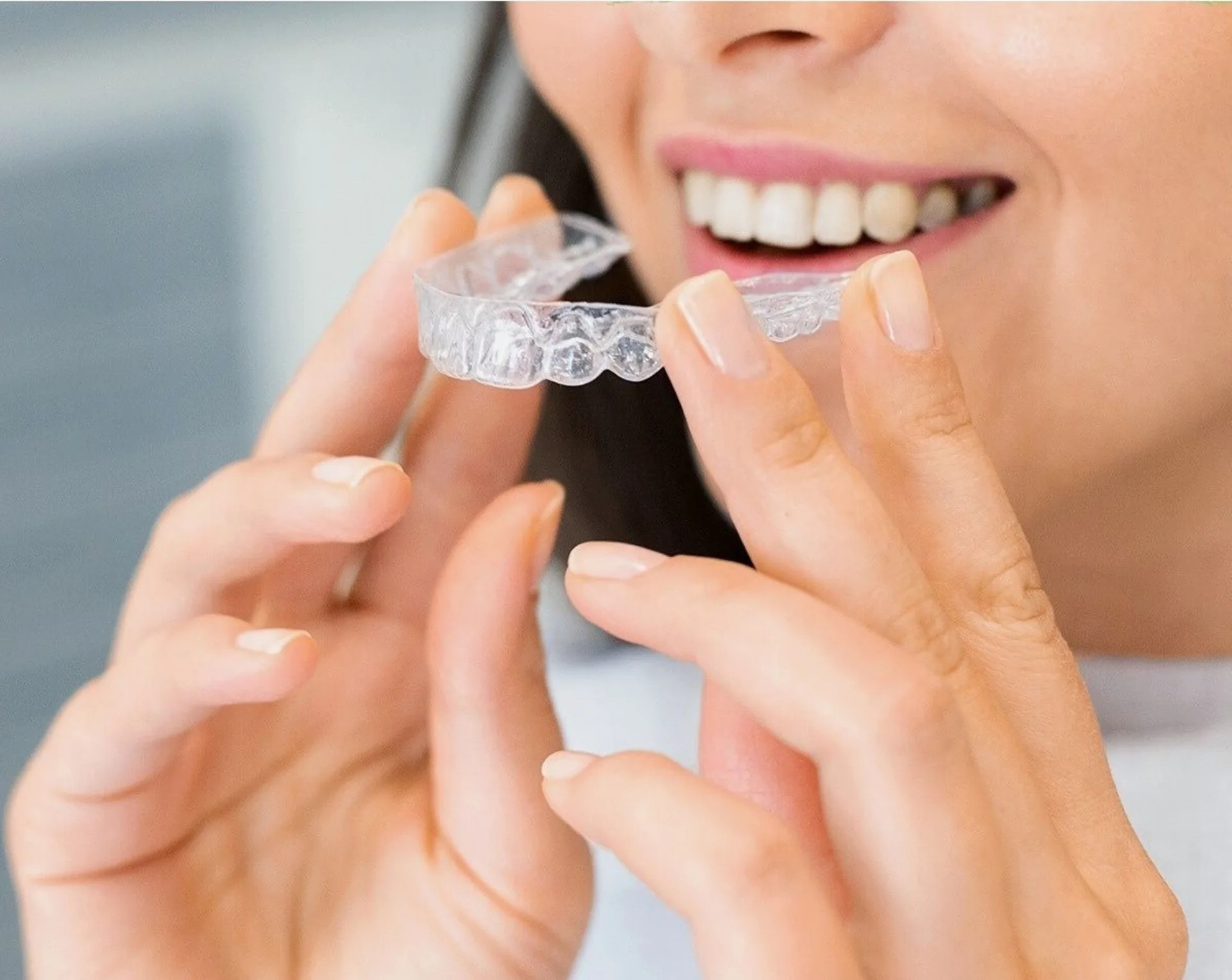 Patient holding a clear aligner for Invisalign treatment at Plaza Dental Arts